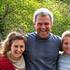 Portrait of David and his family, smiling outdoors.